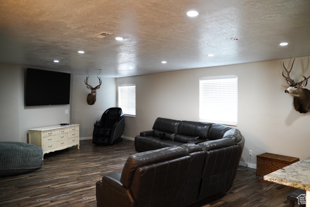 Living room featuring dark wood-type flooring, baseboards, and recessed lighting