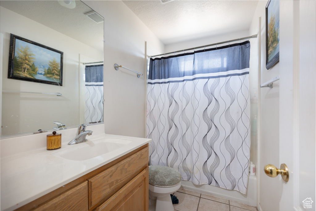 Bathroom featuring vanity, toilet, tile patterned flooring, and shower / bathtub combination with curtain