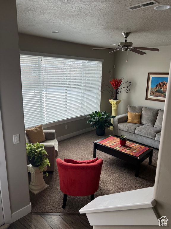 Living room featuring ceiling fan, baseboards, a textured ceiling, and wood finished floors
