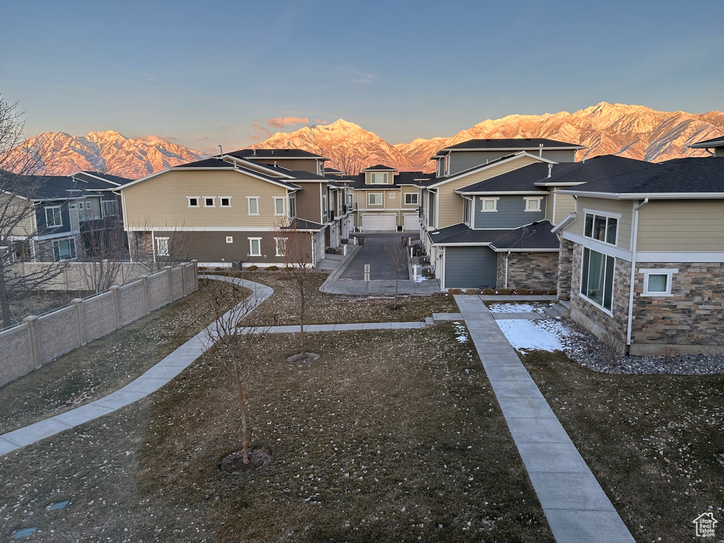 Back of property with a mountain view, a residential view, stone siding, and a patio