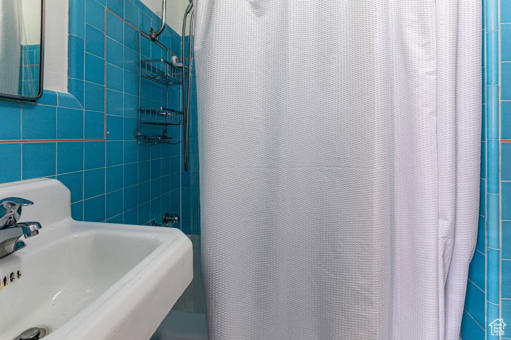 Bathroom featuring a sink, curtained shower, and tile walls