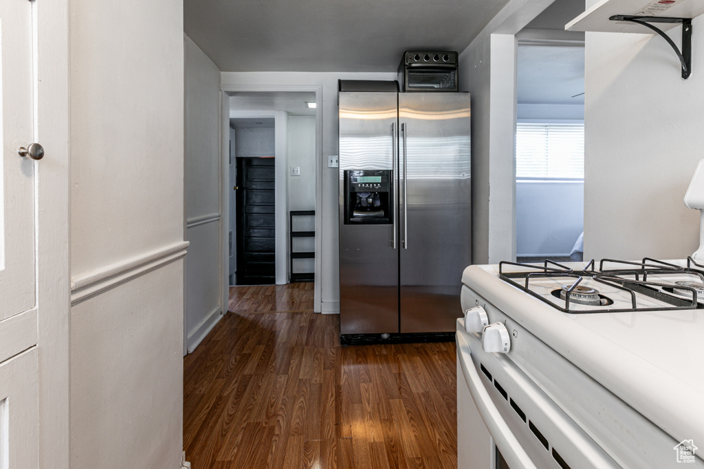 Kitchen featuring stainless steel fridge, white range with gas cooktop, and dark wood finished floors