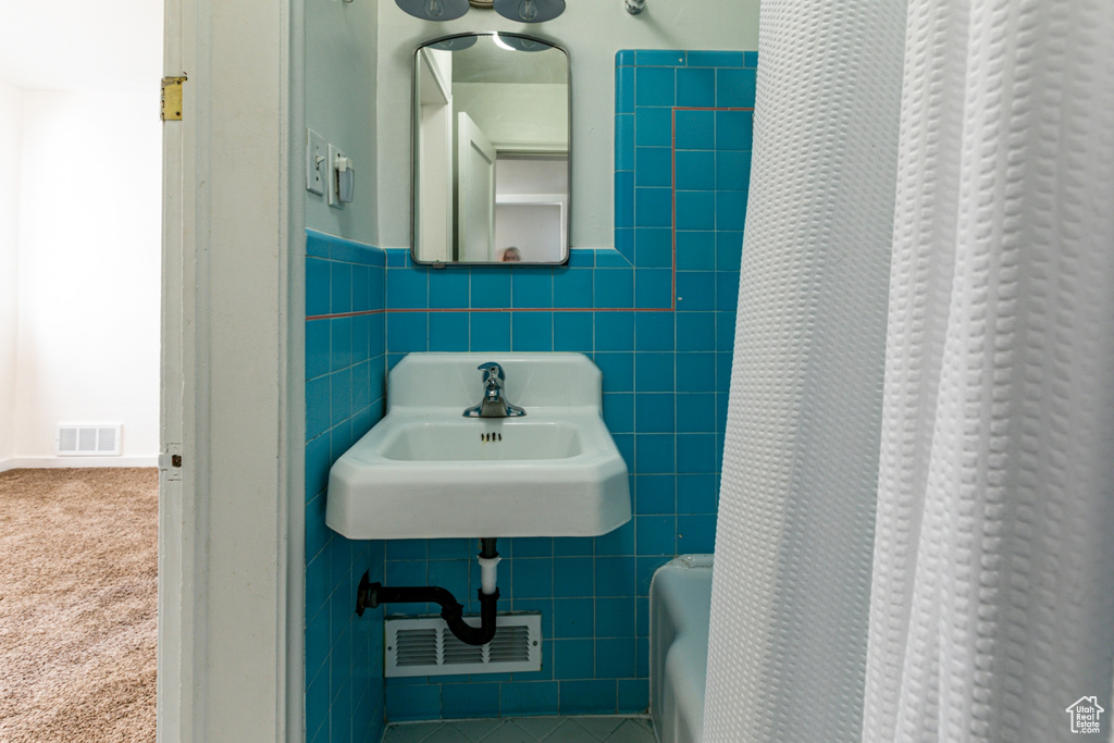 Bathroom featuring tile walls, a wainscoted wall, and a sink