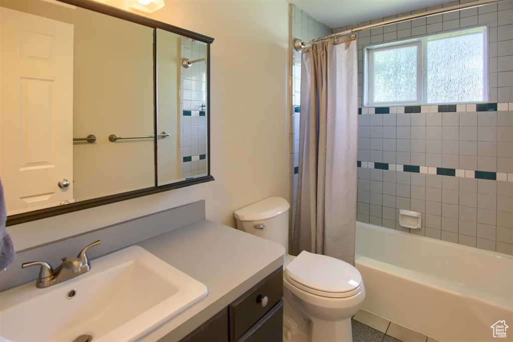 Full bathroom with toilet, vanity, shower / bath combo with shower curtain, and tile patterned flooring