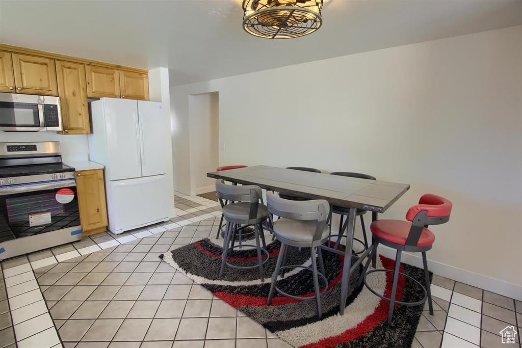 Kitchen featuring appliances with stainless steel finishes, light brown cabinetry, light tile patterned floors, light countertops, and baseboards