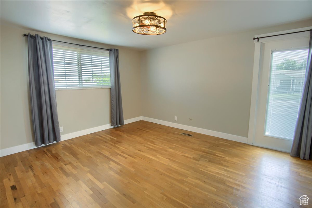 Unfurnished room featuring plenty of natural light, light wood-style floors, and baseboards