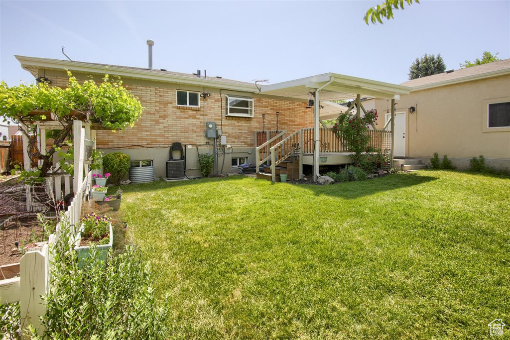 Rear view of house with a yard, brick siding, and cooling unit