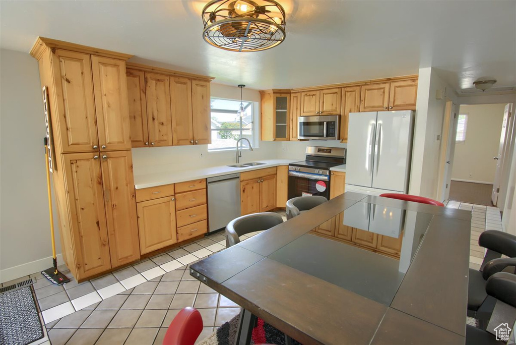 Kitchen featuring stainless steel appliances, a sink, light tile patterned floors, and light brown cabinets