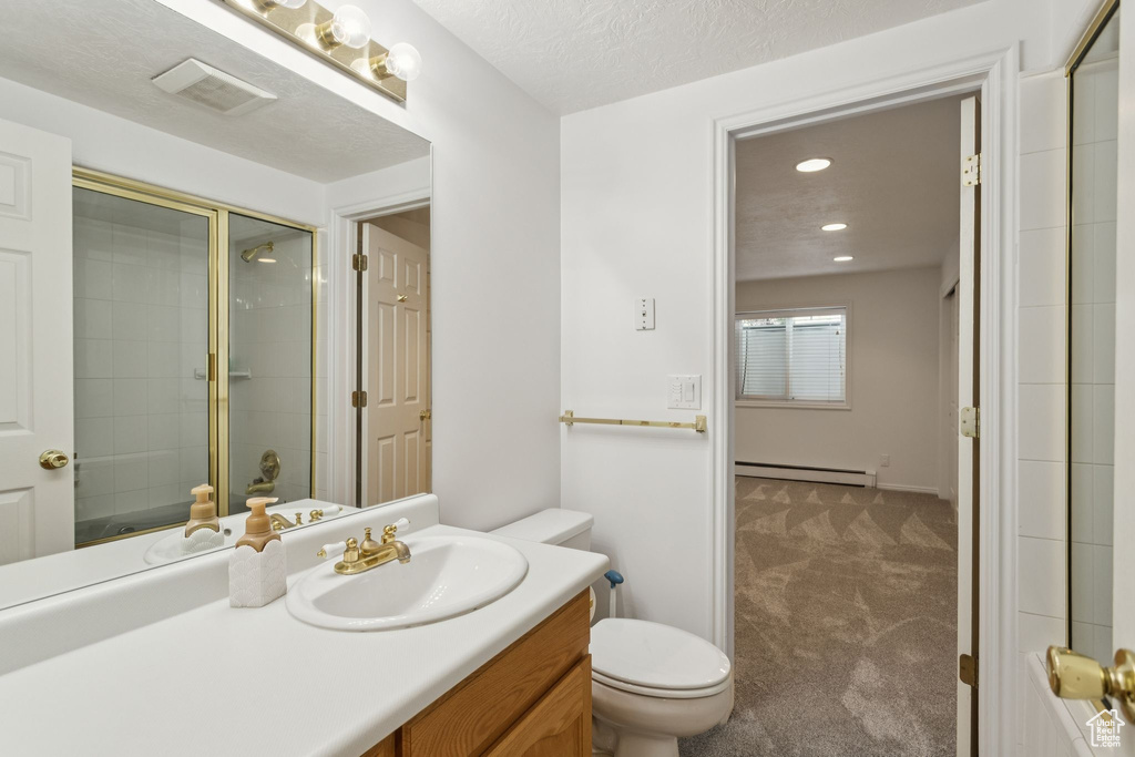 Bathroom with a baseboard radiator, a tile shower, toilet, vanity, and recessed lighting