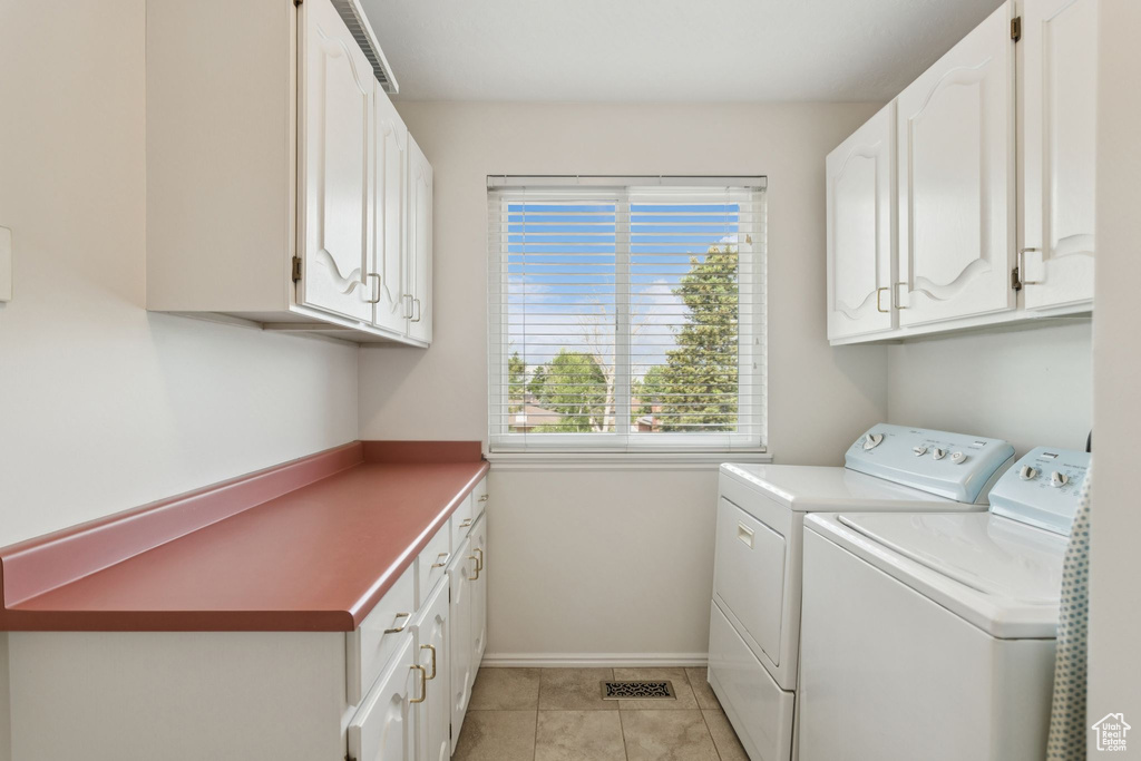 Washroom featuring washer and dryer, cabinet space, baseboards, and light tile patterned floors