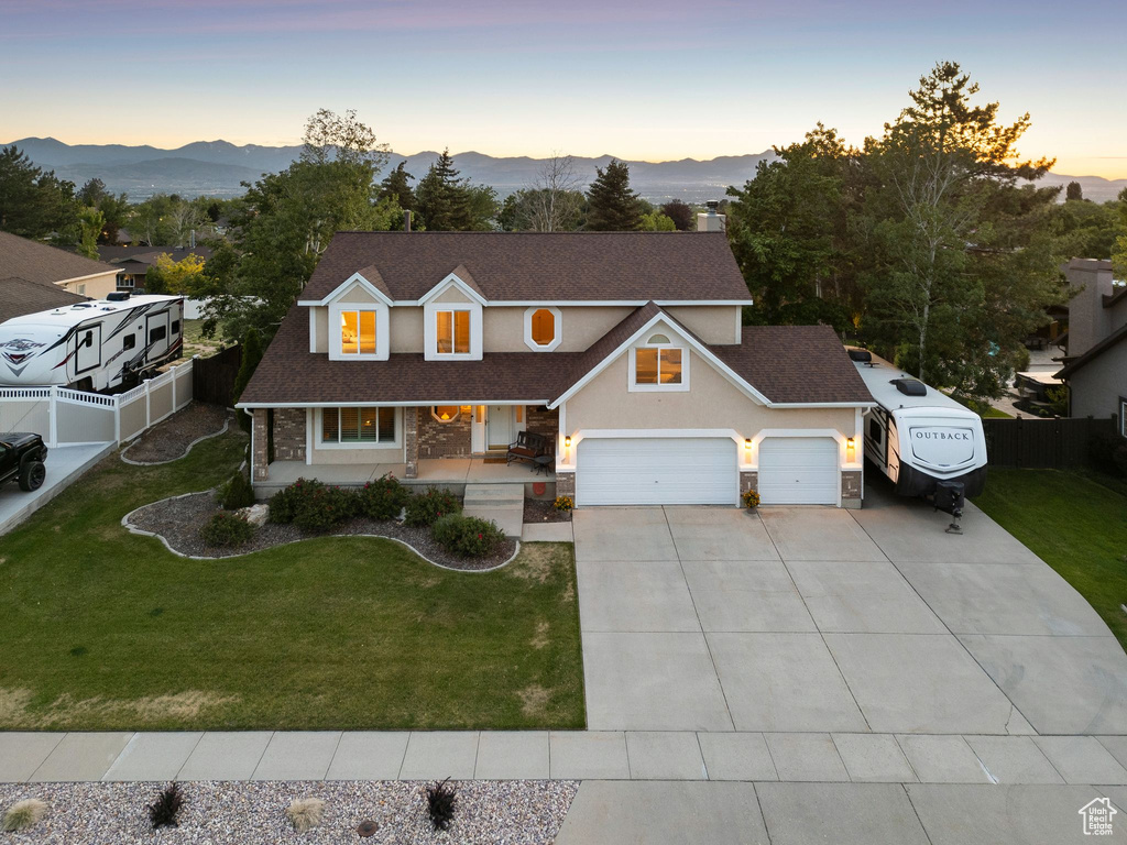 Traditional home featuring covered porch, driveway, a garage, a mountain view, and roof with shingles
