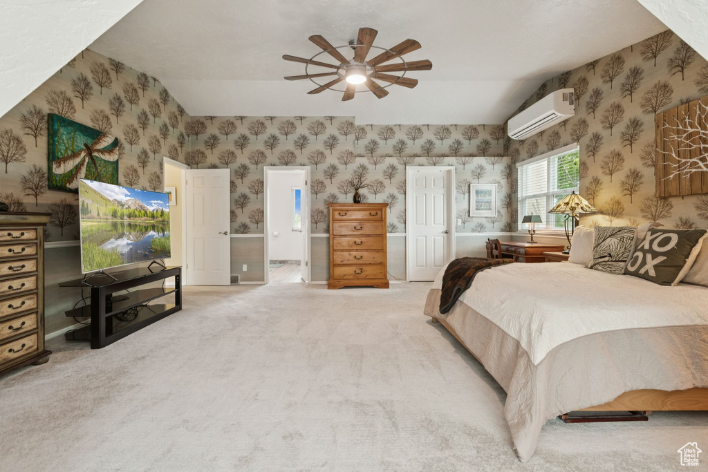 Carpeted bedroom featuring a wall unit AC, wallpapered walls, a ceiling fan, and connected bathroom