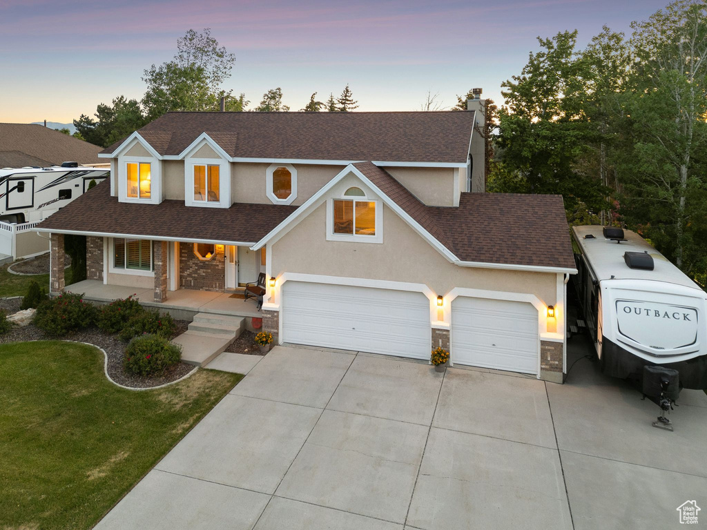 Traditional home featuring driveway, a shingled roof, covered porch, a chimney, and stone siding
