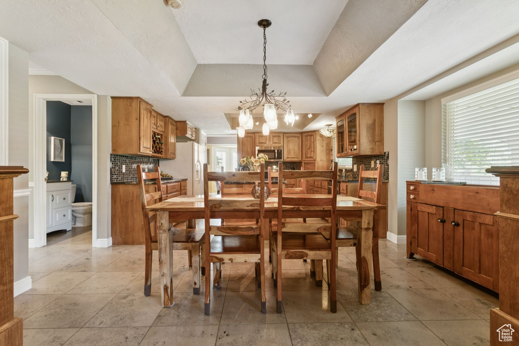 Dining room featuring a chandelier, baseboards, and a raised ceiling