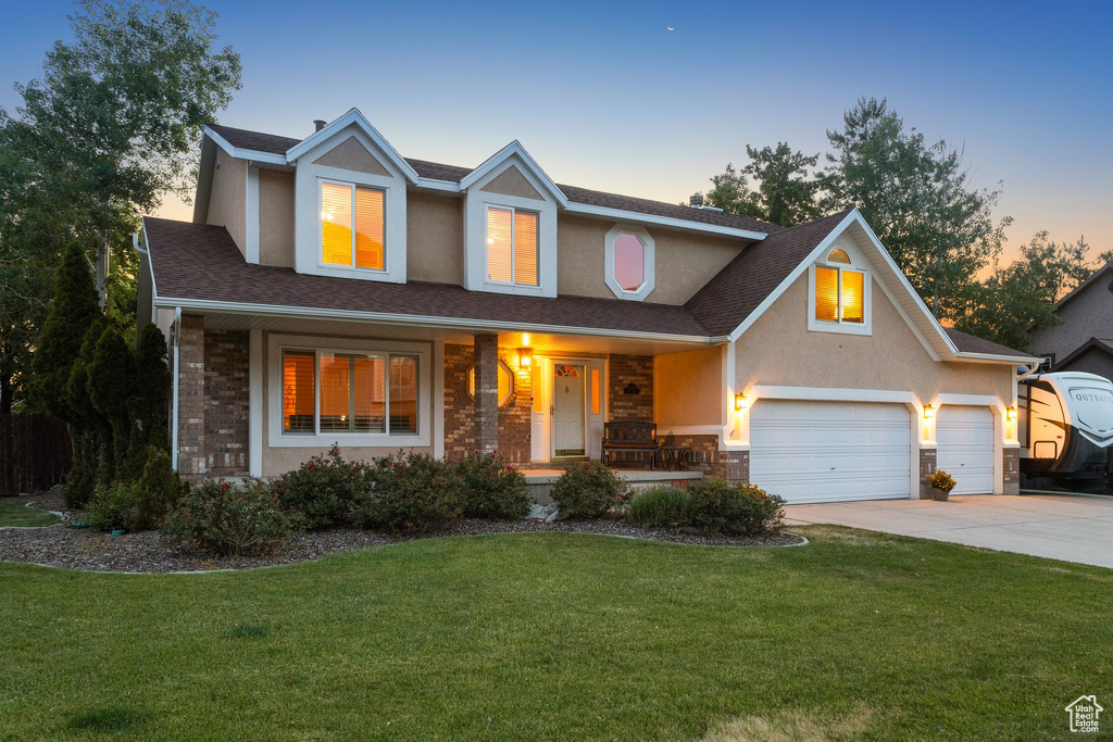 Traditional-style house with driveway, a porch, a front yard, stucco siding, and a shingled roof