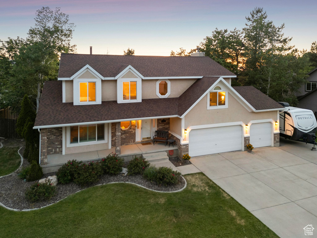 Traditional-style house featuring a shingled roof, covered porch, driveway, and a garage