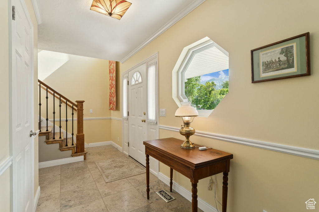 Entrance foyer featuring stairs, crown molding, and baseboards