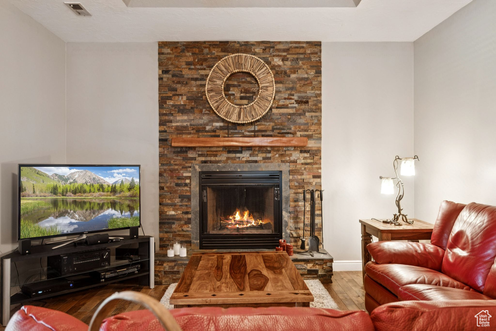 Living area with hardwood / wood-style flooring and a stone fireplace