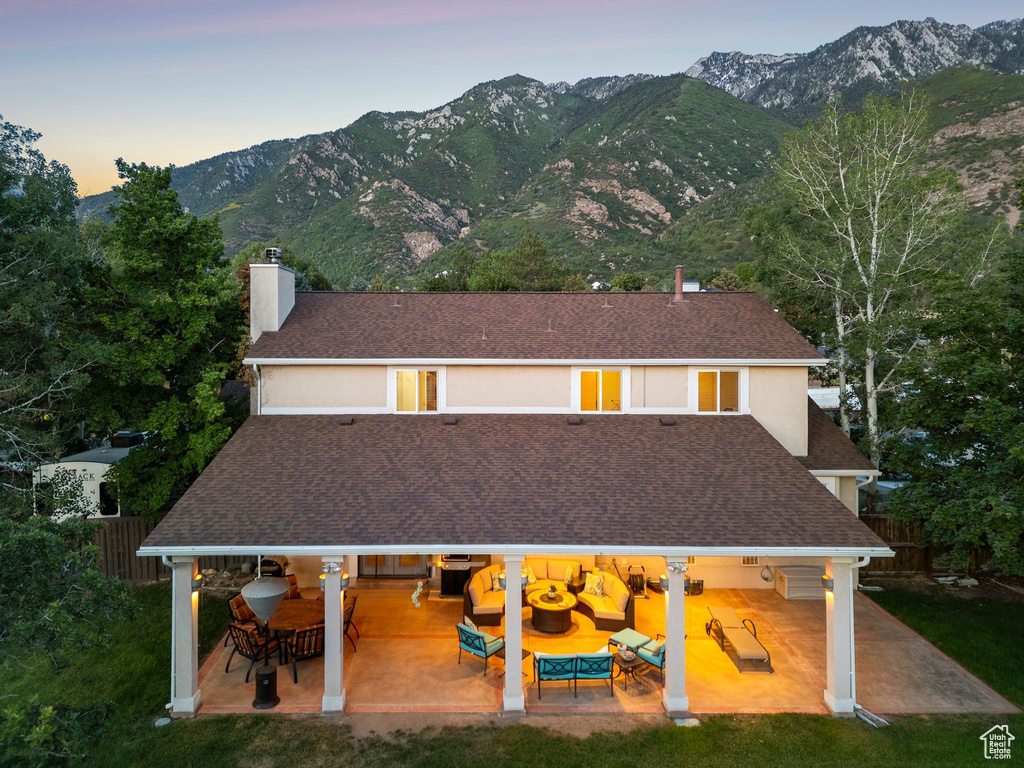 View of front facade with a patio area, a chimney, roof with shingles, and a mountain view