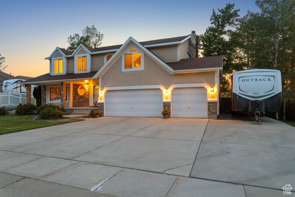 Traditional-style home with stucco siding, driveway, stone siding, a garage, and a porch