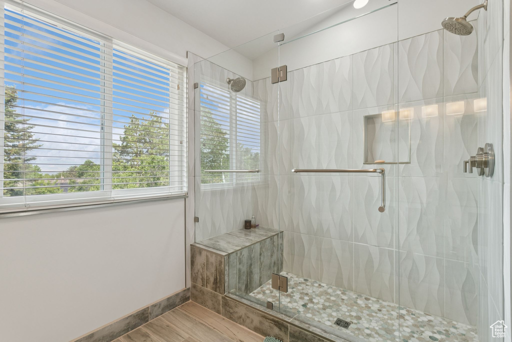 Bathroom featuring wood finished floors, a stall shower, healthy amount of natural light, and baseboards