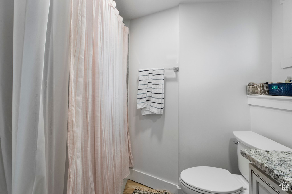 Full bathroom with toilet, vanity, a shower with curtain, and baseboards