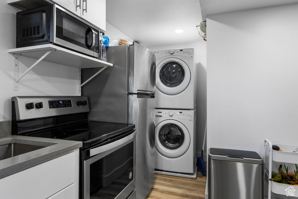 Laundry room featuring estacked washer and dryer, light wood-style flooring, and recessed lighting