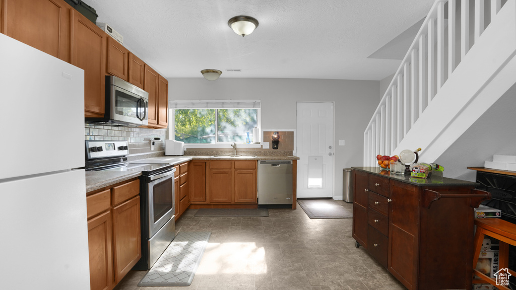 Kitchen with appliances with stainless steel finishes, a sink, backsplash, and a kitchen breakfast bar