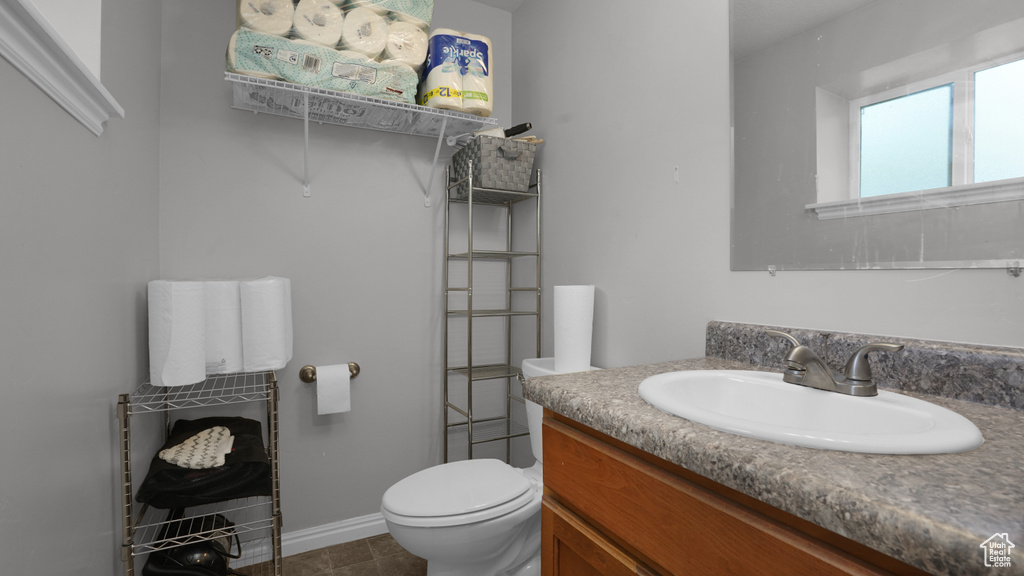 Bathroom with vanity, toilet, tile patterned flooring, and baseboards