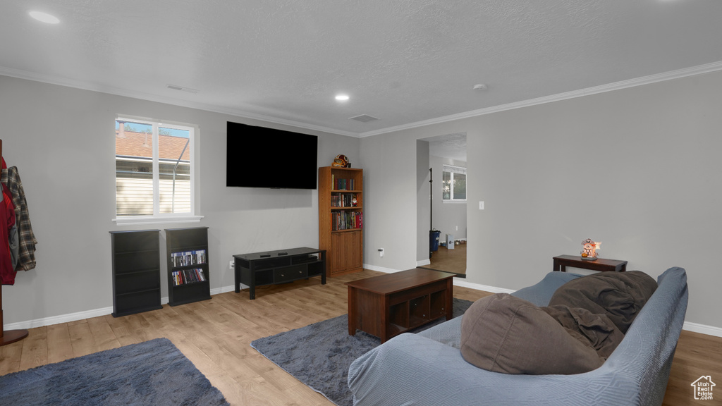 Living room with ornamental molding, wood finished floors, healthy amount of natural light, baseboards, and recessed lighting