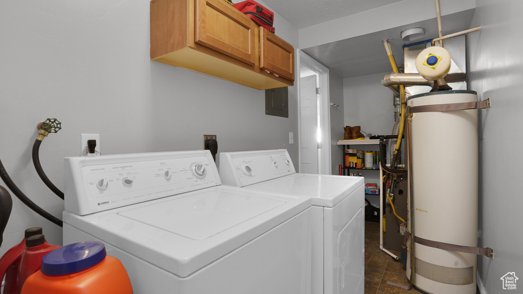 Washroom featuring separate washer and dryer, cabinet space, gas water heater, electric panel, and dark stone finish floors