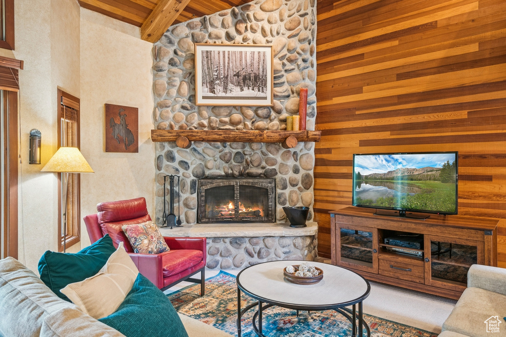 Living area featuring a fireplace, wooden ceiling with exposed beams, wood walls, and high vaulted ceiling