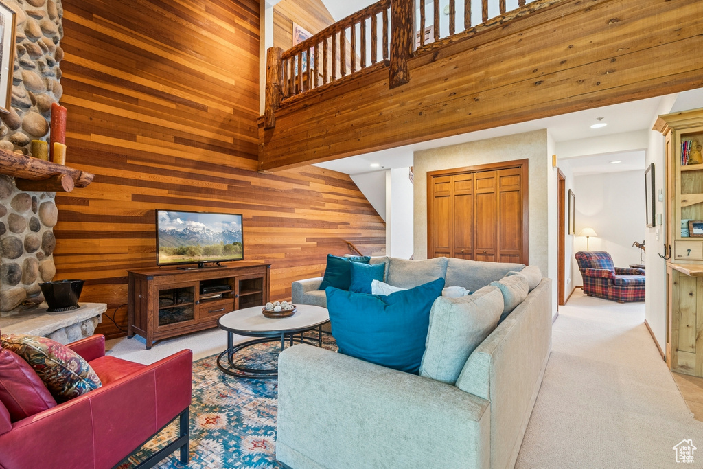 Living area with wood walls, stairs, carpet, and a high ceiling
