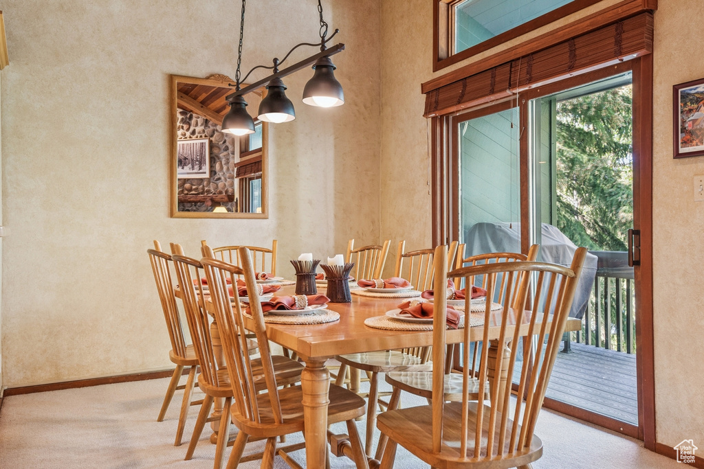 Dining area featuring baseboards, carpet, a textured wall, and a high ceiling