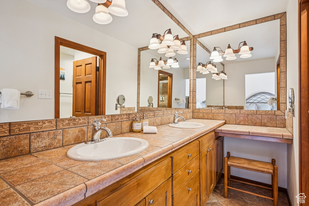 Full bath with a chandelier, double vanity, tasteful backsplash, and tile patterned floors