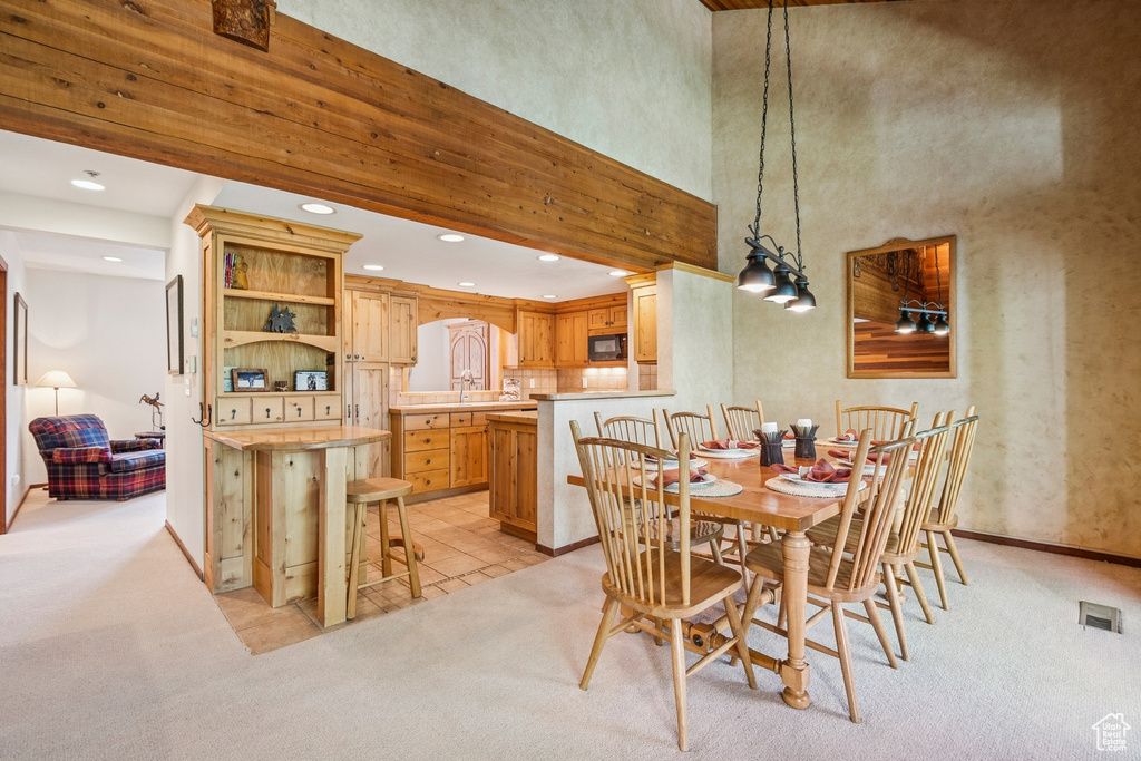 Dining area featuring light colored carpet, recessed lighting, baseboards, and a towering ceiling
