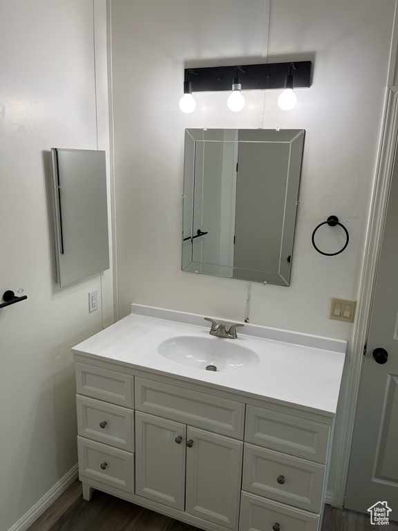 Bathroom with vanity, wood finished floors, and baseboards