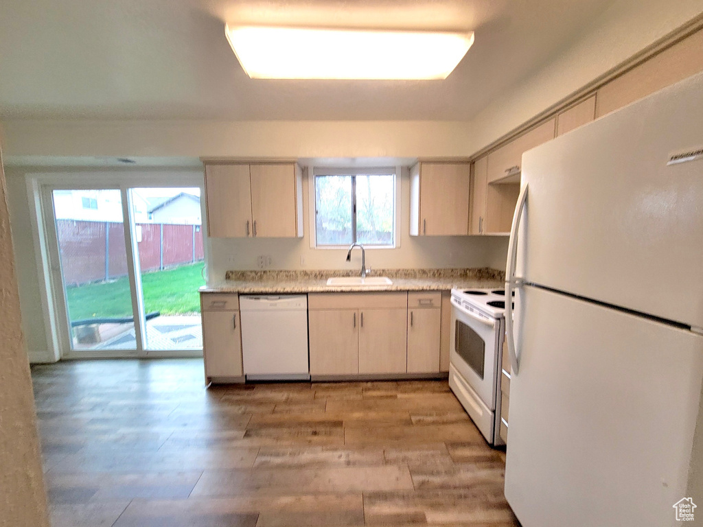 Kitchen featuring white appliances, a sink, light countertops, and light wood-style floors