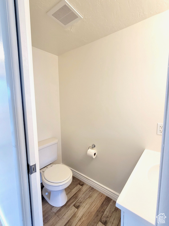 Bathroom with vanity, wood finished floors, toilet, and baseboards