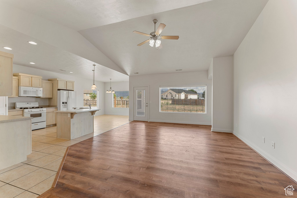 Unfurnished living room featuring plenty of natural light, ceiling fan, lofted ceiling, light wood-type flooring, and recessed lighting
