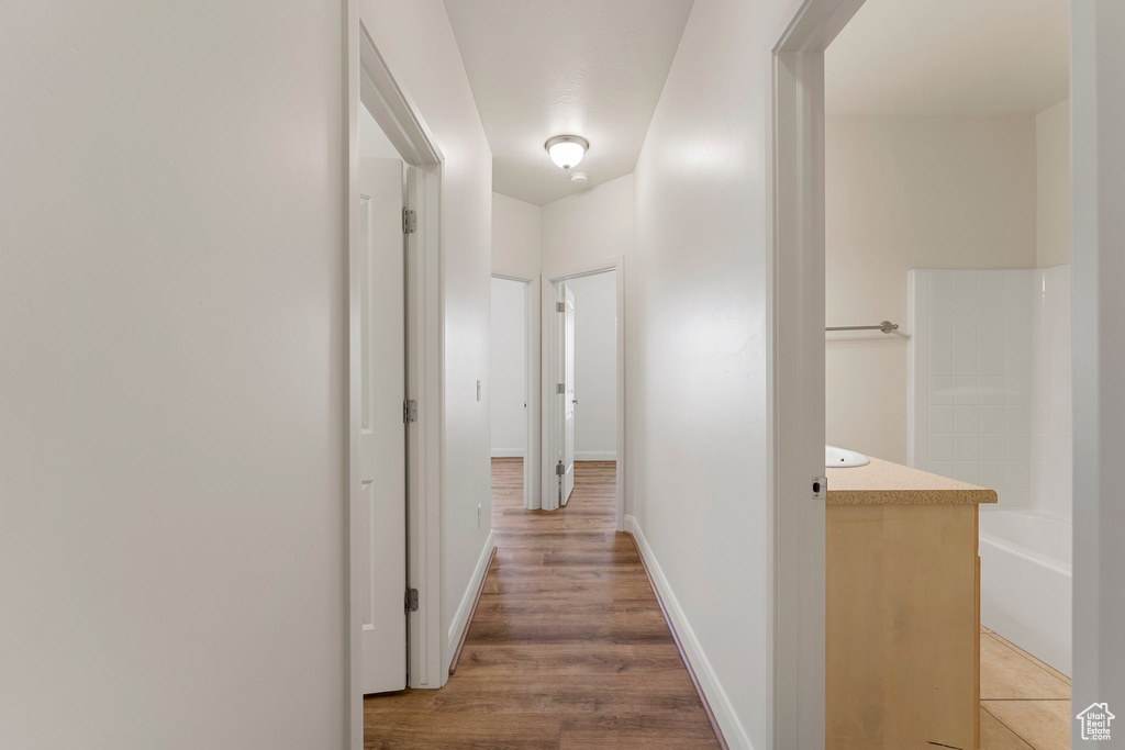 Corridor with light wood-style flooring and baseboards