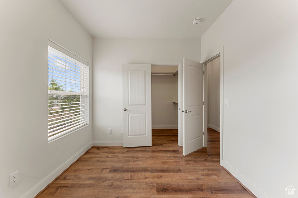 Unfurnished bedroom featuring light wood-style flooring, baseboards, a spacious closet, and a closet