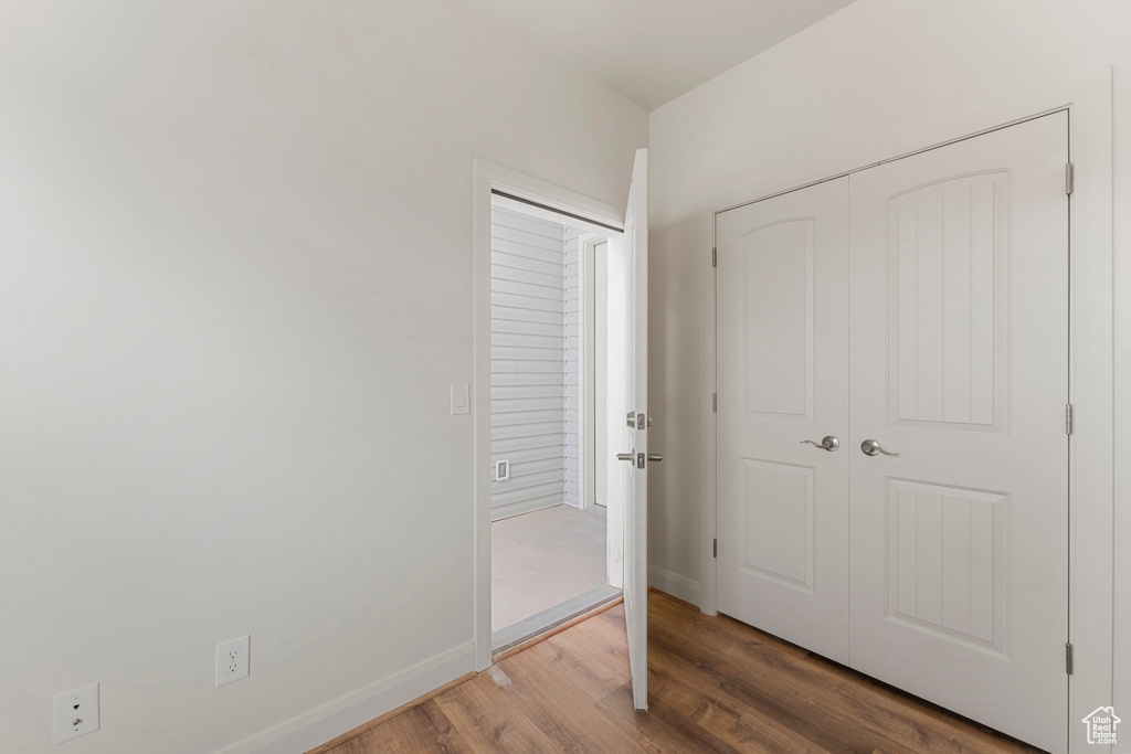 Unfurnished bedroom with wood finished floors, a closet, and baseboards