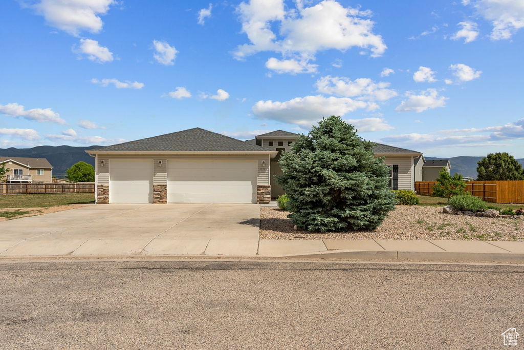 View of front of home with a mountain view, driveway, stone siding, and an attached garage