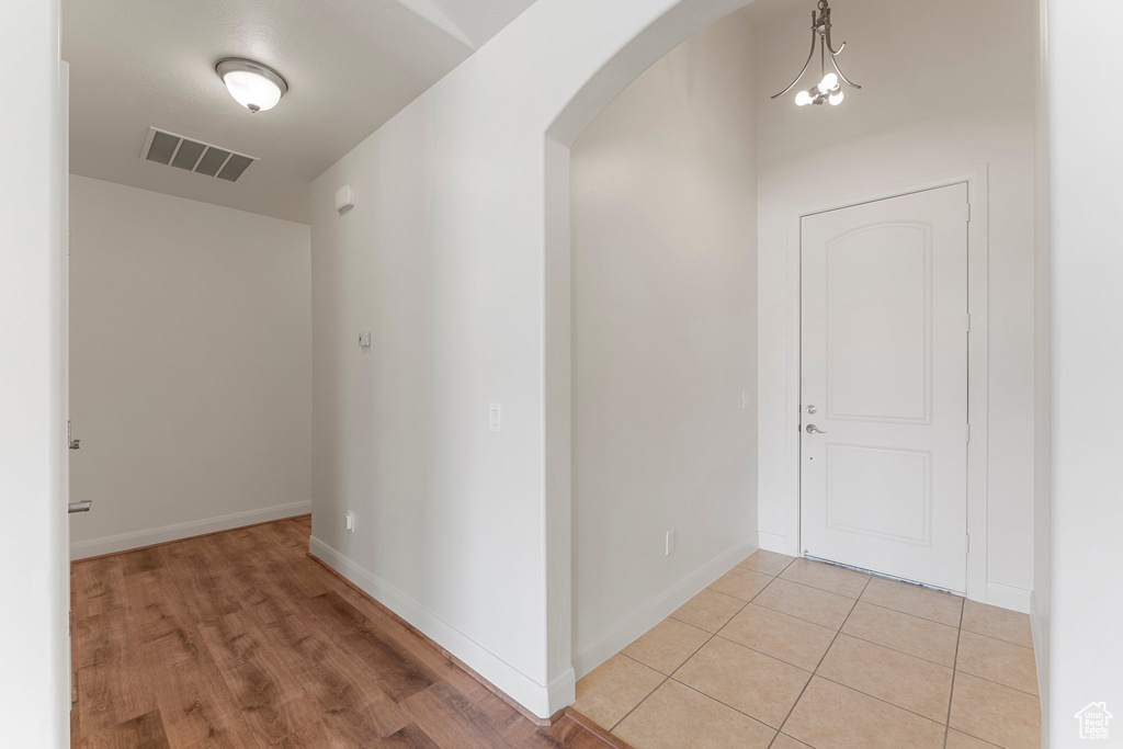 Hallway featuring arched walkways, baseboards, and light wood-style floors