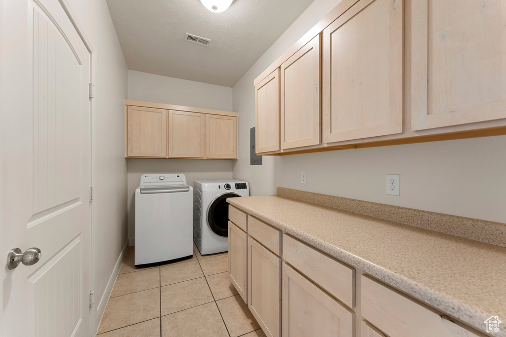 Laundry area featuring washing machine and clothes dryer, cabinet space, and light tile patterned floors