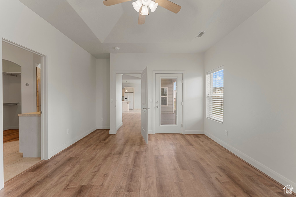 Spare room featuring ceiling fan, arched walkways, light wood-style floors, and baseboards