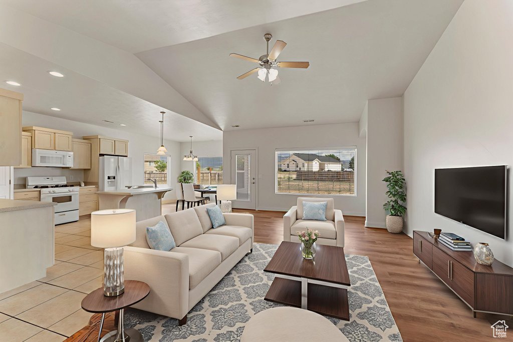 Living room featuring healthy amount of natural light, ceiling fan, lofted ceiling, recessed lighting, and light wood-style floors