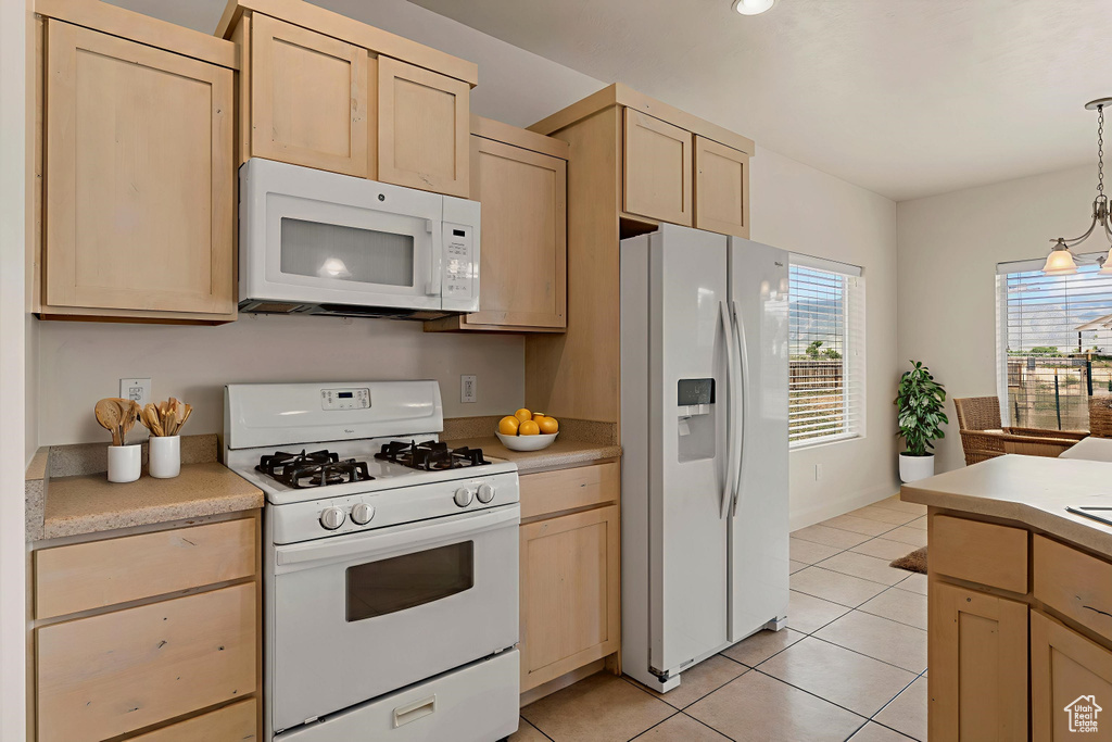 Kitchen with white appliances, light brown cabinets, and light tile patterned floors