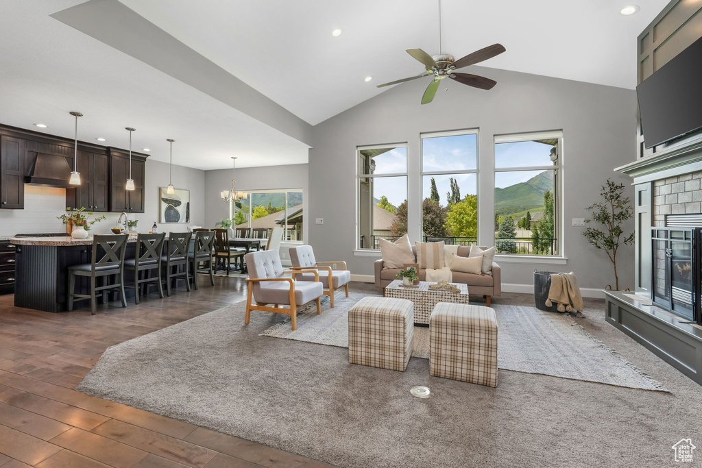 Living room featuring high vaulted ceiling, recessed lighting, ceiling fan, a glass covered fireplace, and wood finished floors